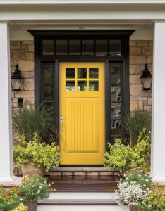 A close-up image of a home's entryway with decorative stone and a yellow front door with glass accents.